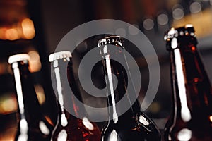 Glass bottles of beer on dark pub background