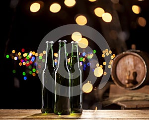 Glass bottles of beer and wooden barrel on bar lights background