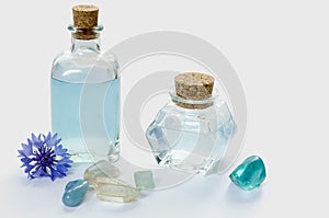 Glass bottles with blue cornflower flower water or essential oil, minerals and plant on white background, SPA or phytotherapy