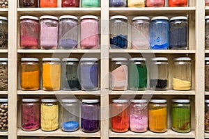 Glass bottles with colorful spices on the shelfs