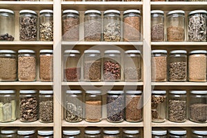 Glass bottles with colorful spices on the shelfs