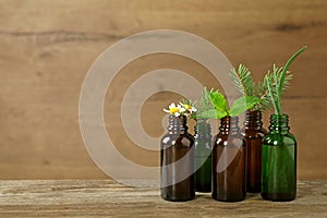 Glass bottles of different essential oils with  on table. Space for text