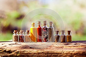 Glass bottles with different spices on wooden board
