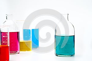 Glass bottles and flasks of different sizes with liquids of different colors on the background. Chemical lab.