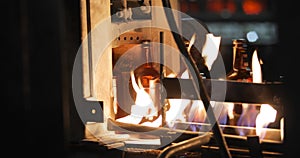 Glass bottles move along conveyor line fall under open flame to glass hardening.