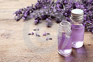 Glass bottles of natural cosmetic oil and lavender flowers on table, space for text