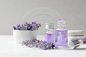 Glass bottles of natural cosmetic oil and lavender flowers on wooden table