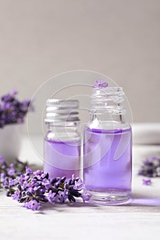 Glass bottles of natural cosmetic oil and lavender flowers on wooden table