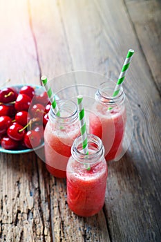 Glass bottles with a red smoothies made with red berries and fruits.