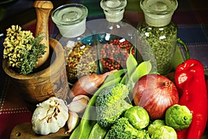 Glass bottles with spices, fresh red and green vegetables, broccoli, tomatoes, garlic, onion