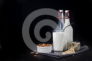 glass and bottles of vegetarian oatmeal and almond milk on dark background