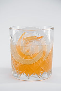Glass of Boulevardier cocktail with big ice cube and orange zest, classic cocktail Boozy Boulevardier with Orange and