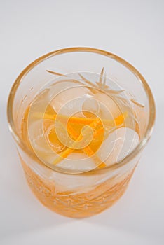 Glass of Boulevardier cocktail with big ice cube and orange zest, classic cocktail Boozy Boulevardier with Orange and