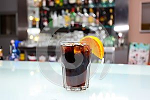 Glass of Boulevardier cocktail with big ice cubes and orange slice. Classic alcoholic drink composed of whiskey, sweet vermouth,