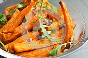 Glass bowl with baked sweet potato slices and arugula