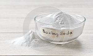 Glass bowl of baking soda on a light wooden table