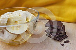 Glass bowl of bananas and dark chocolate on the side