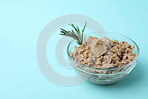 Glass bowl with canned tuna on blue background
