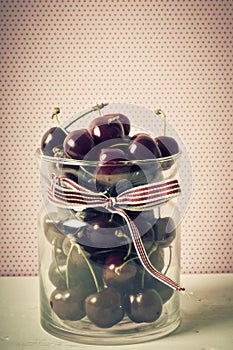 A glass bowl with cherries in old retro vintage style