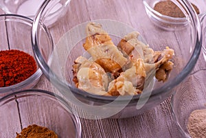 Glass bowl of chicken wings surrounded by glass bowls of spices