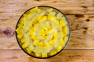 Glass bowl with chopped pineapple on wooden table. Top view