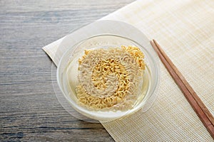 Glass bowl , chopsticks and instant noodle on the wooden table