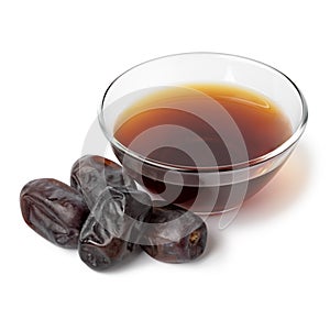 Glass bowl with date vinegar and dried dates in front on white background