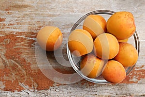 Glass bowl with delicious ripe apricots on wooden table, flat lay