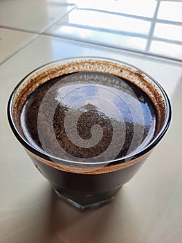 A glass bowl filled with black coffee, a dark brown liquid, served to awaken and invigorate the senses photo