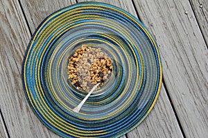 Glass bowl of flavorful granola on colorful round placemat