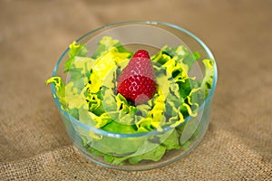Glass bowl with fresh green salad pained fresh fruit