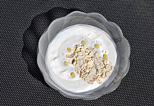 Glass bowl with fresh plain yogurt and oat flakes