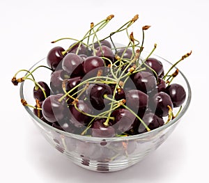 A glass bowl full with sweet cherries isolated