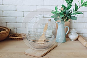 Glass bowl with groats and various kitchen utensils and dishware on wooden table