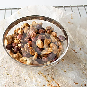 Glass bowl of mixed nuts on parchment paper and cooling rack