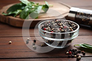 Glass bowl of mixed pepper corns on wooden table