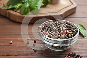 Glass bowl of mixed pepper corns on wooden table