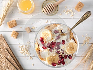 Glass bowl with muesli and yogurt with banana, pomegranate seeds
