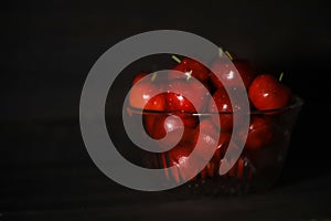 Glass bowl of ripe cherries isolated on dark background