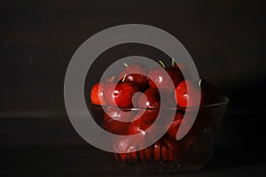 Glass bowl of ripe cherries isolated on dark background