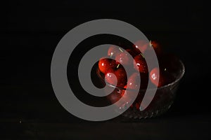 Glass bowl of ripe cherries isolated on dark background