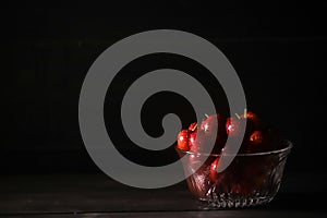 Glass bowl of ripe cherries isolated on dark background