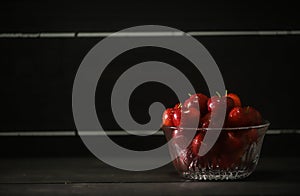 Glass bowl of ripe cherries isolated on dark background