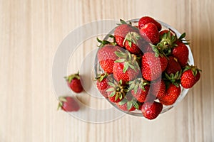 Glass bowl with ripe strawberries on white table, top view. Space for text