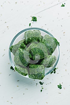 glass bowl with some cubes of frozen spinach