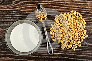 Glass bowl with yogurt, puffed wheat in spoon, on wooden table. Top view