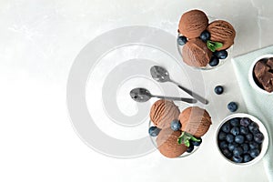 Glass bowls of chocolate ice cream and blueberries served on light table, flat lay