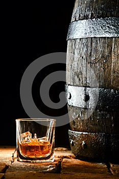 Glass of brandy alongside an oak barrel
