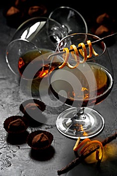 Glass of brandy  or cognac and  chocolate candy  on dark table