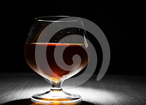 Glass of brandy or cognac on the old dark wooden background